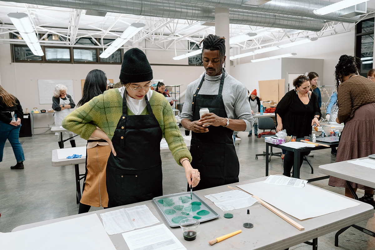 People engaged in an art making activity in a large, open, well lit studio