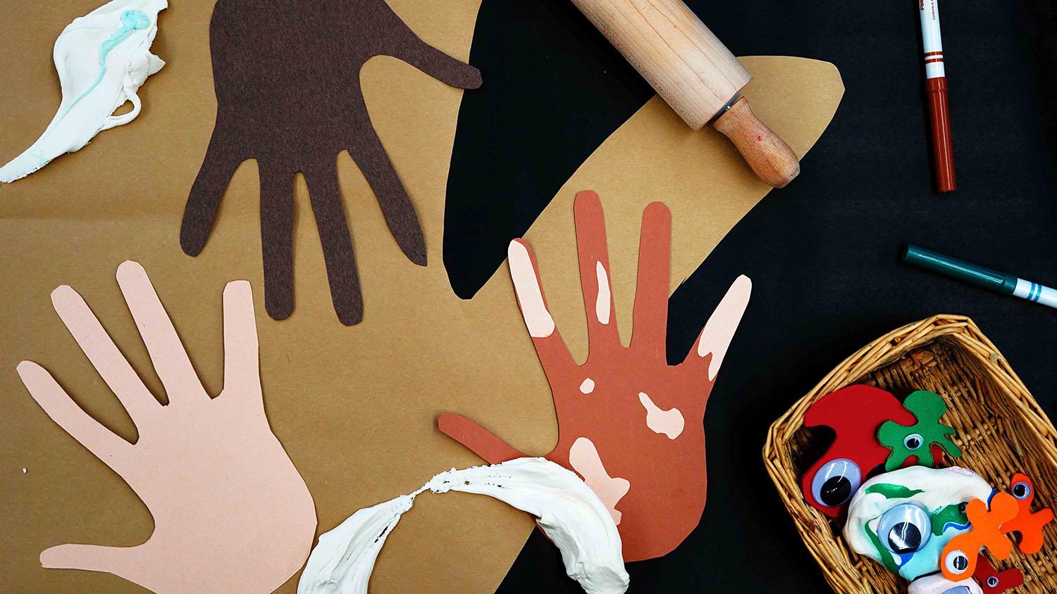 Construction paper hands and a basket containing 'germs' made of clay, paper, and googly eyes