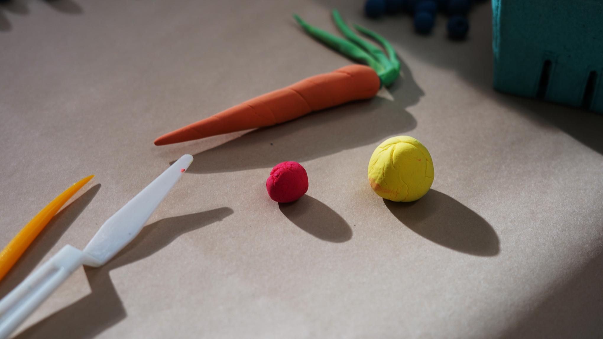 Photo of clay tools and balls of modeling clay and a clay carrot