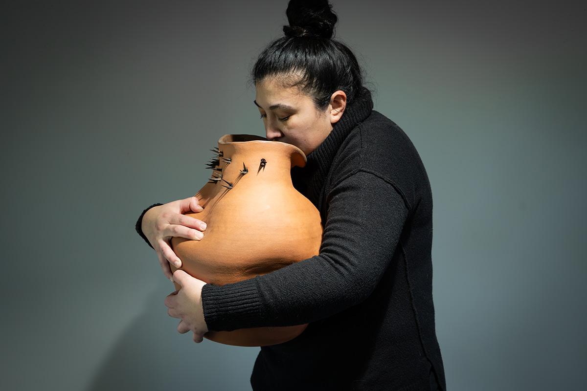 A woman holding a large ceramic vessel