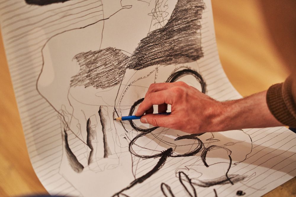 A close up view of a person drawing abstract shapes in charcol