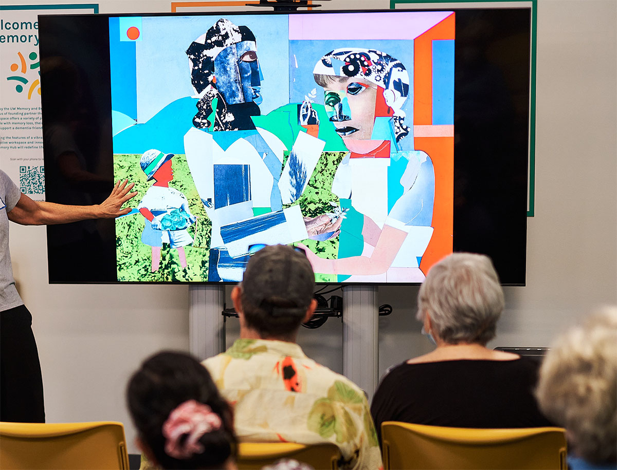 Older people seen from behind looking at an artwork displayed on a screen. An arm appears from outside the image pointing at the artwork.
