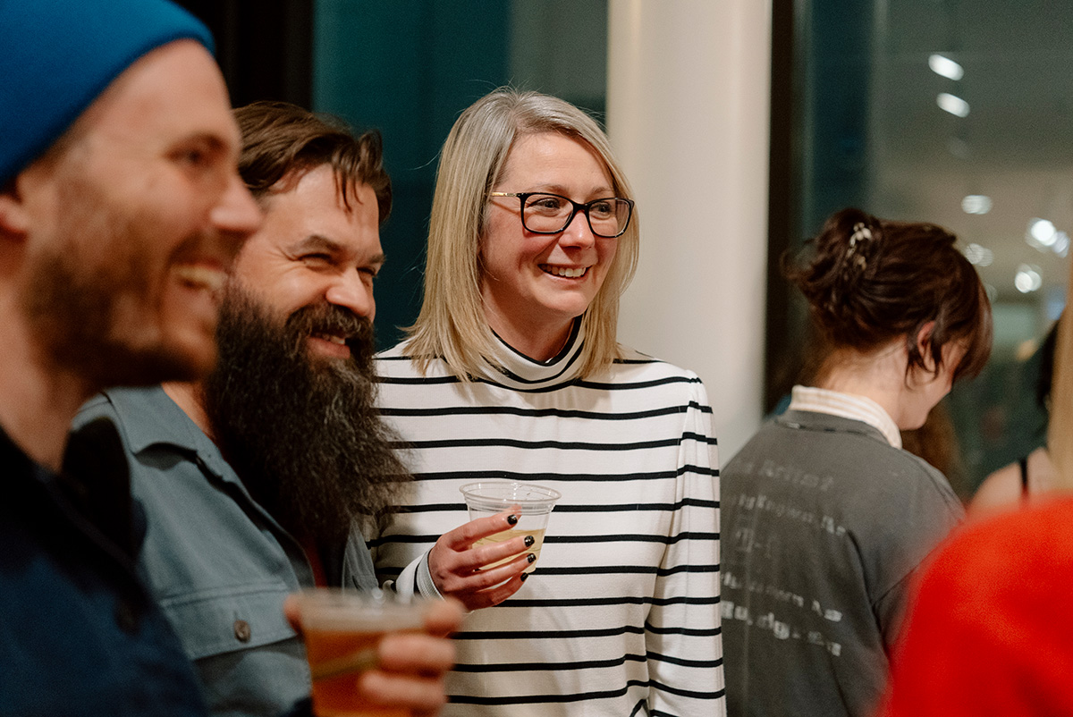 People smiling and chatting in a group while holding disposible glasses of wine