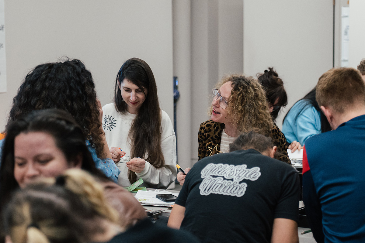 People sitting at long tables with art supplies and chatting