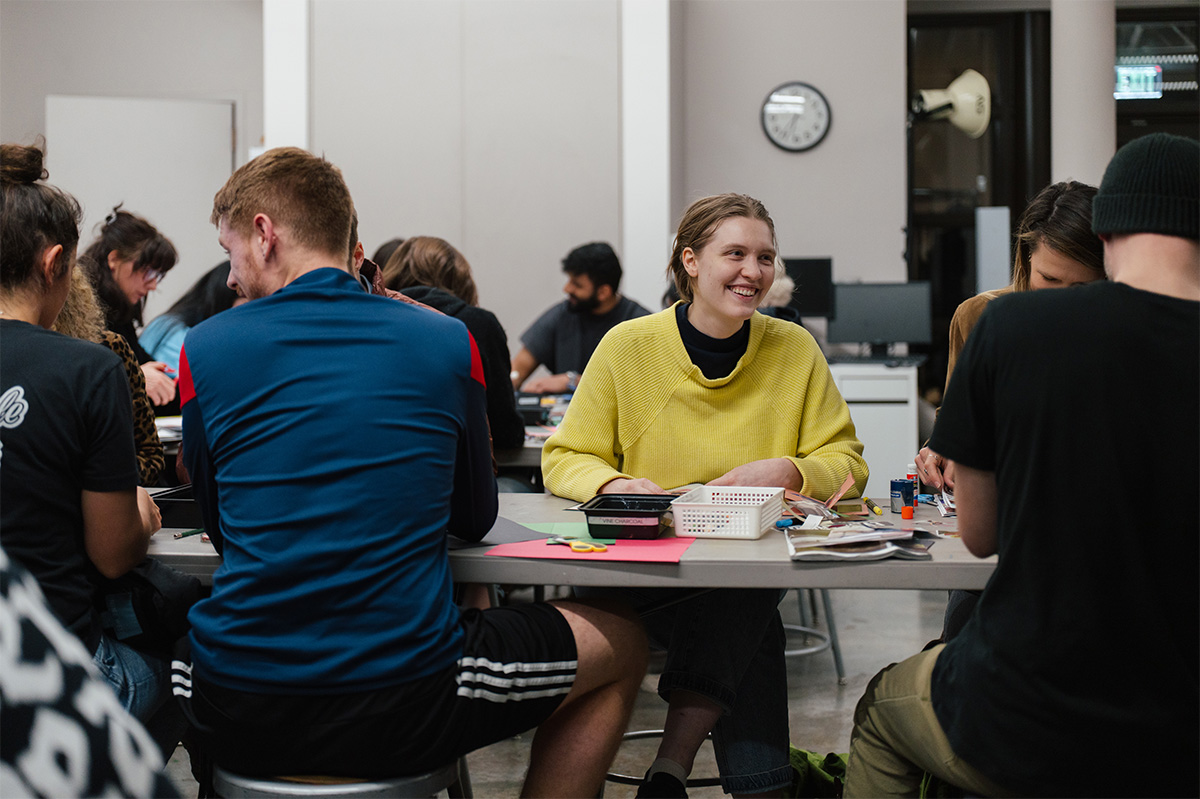 People sitting at a long table and working on art projects
