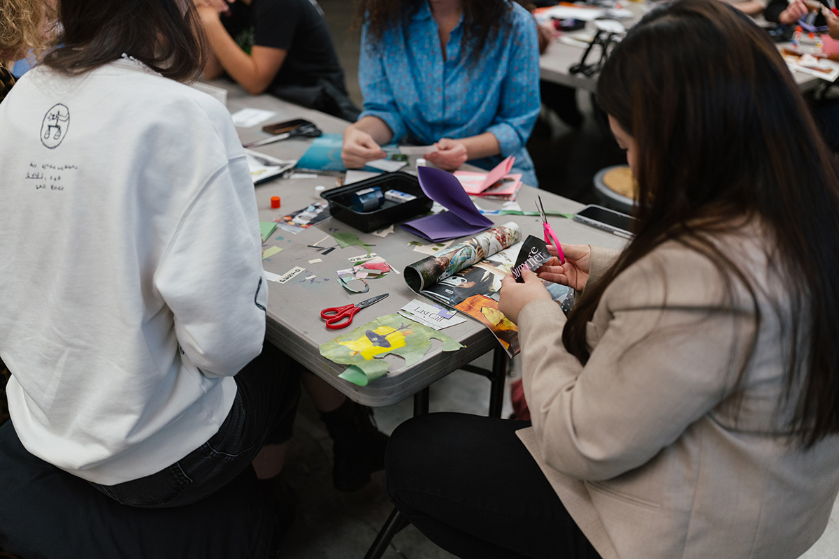 People sitting around a plastic rectangular table working on a collage art project
