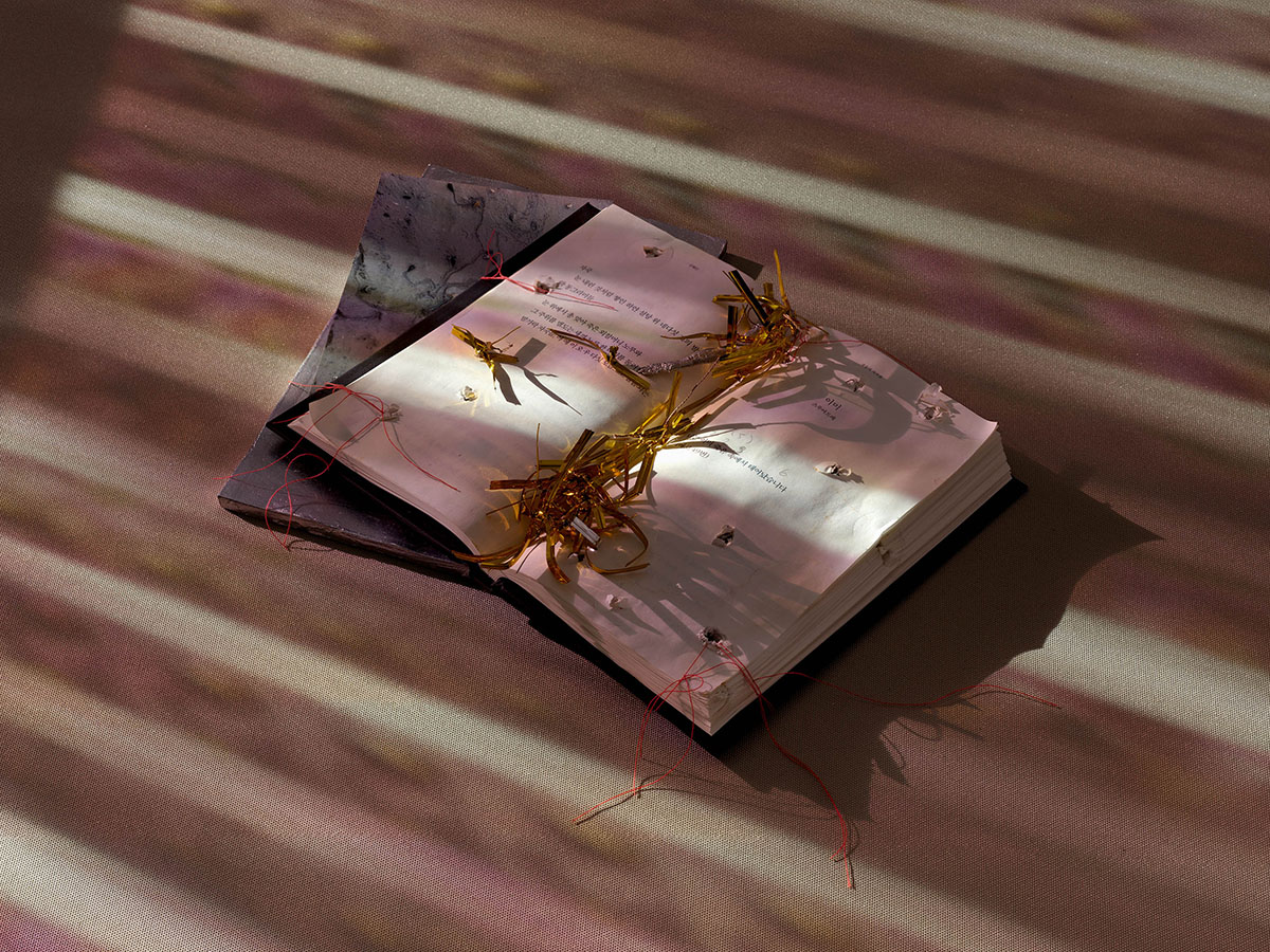 A book lying open on the floor illuminated by strips of dim light