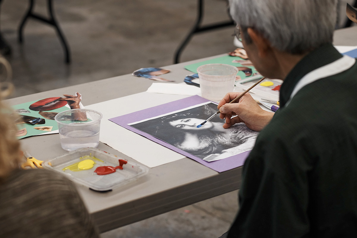 An older adult working on artwork that involves painting over a printed image
