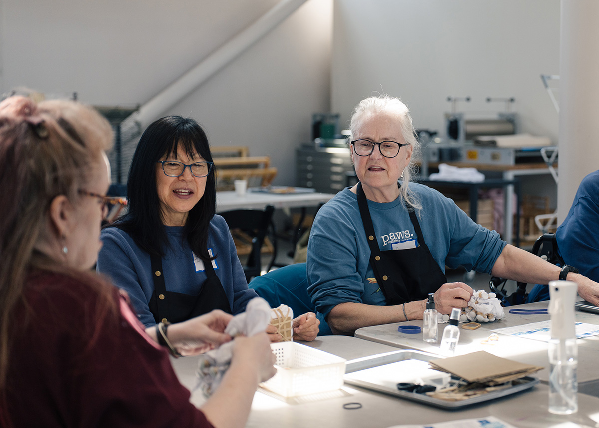People sitting at a table together and working on individual artworks
