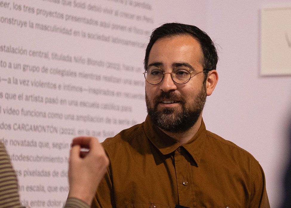 Rafael Soldi in conversation in front of the exhibition text for Rafael Soldi: Soft Boy