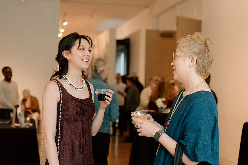 Two women smiling and talking while holding cups of wine