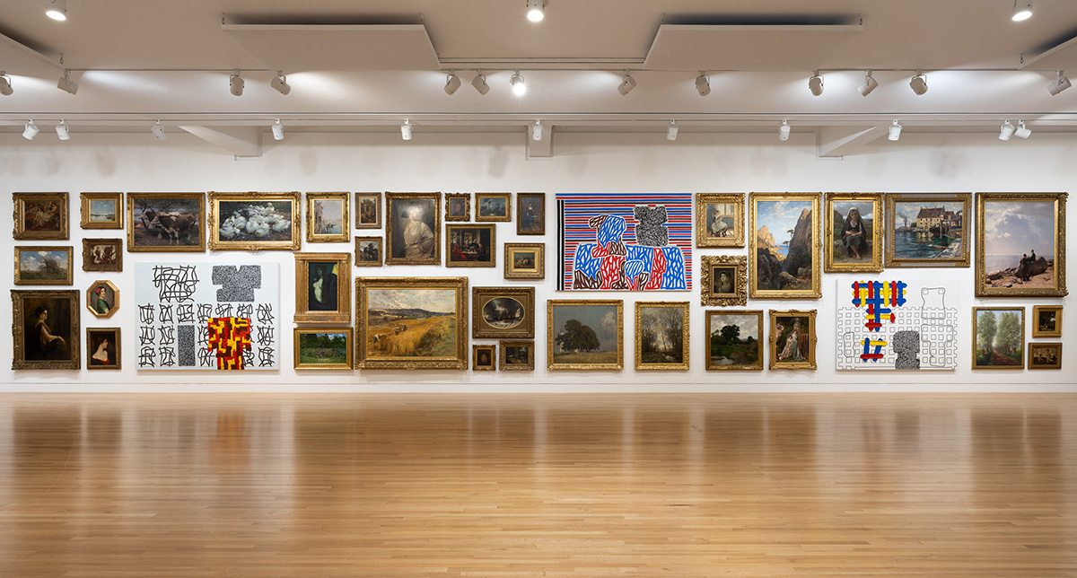 A wide view of a large gallery space. The facing wall is covered in tightly laid out paintings, some historical and representative and some abstract.