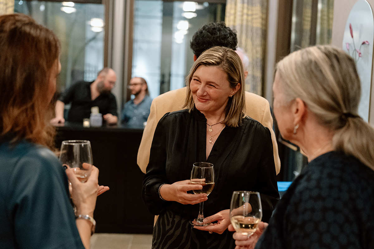 A small group of people holding glasses of wine and chatting