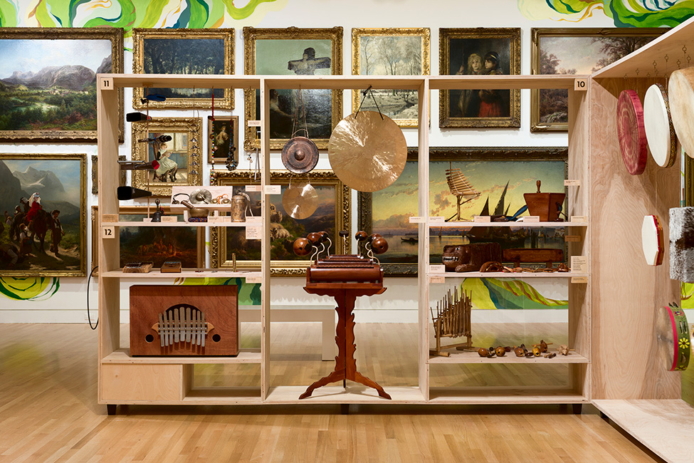 A view of instruments in the exhibition LINEAJES in front of the paintings of the Frye Salon
