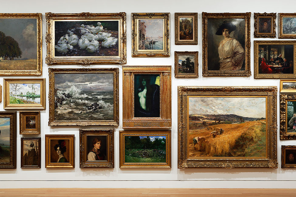 Paintings hanging on a wall, salon-style, in the Frye Art Museum