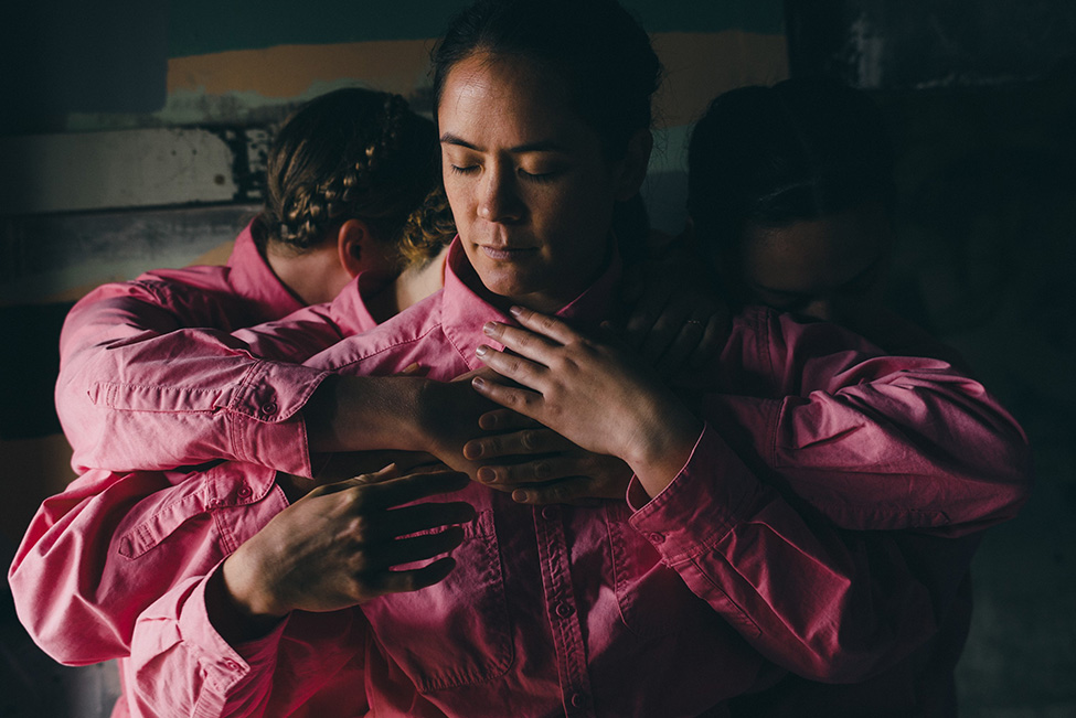 People in pink jumpsuits with their arms wrapped around one person