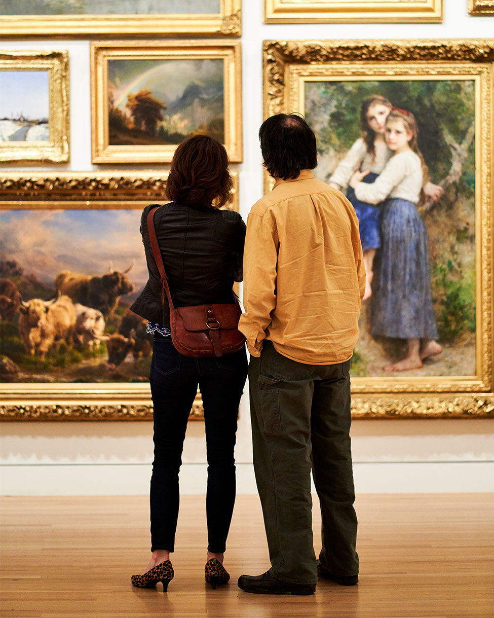 Two people looking at paintings in the Frye Salon