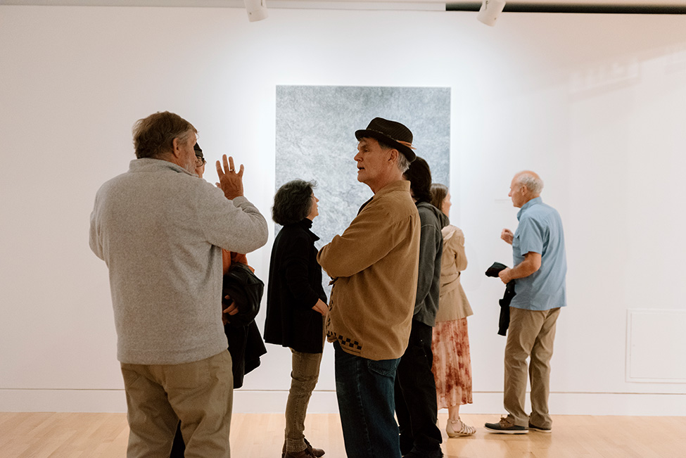 People chatting in front of an artwork