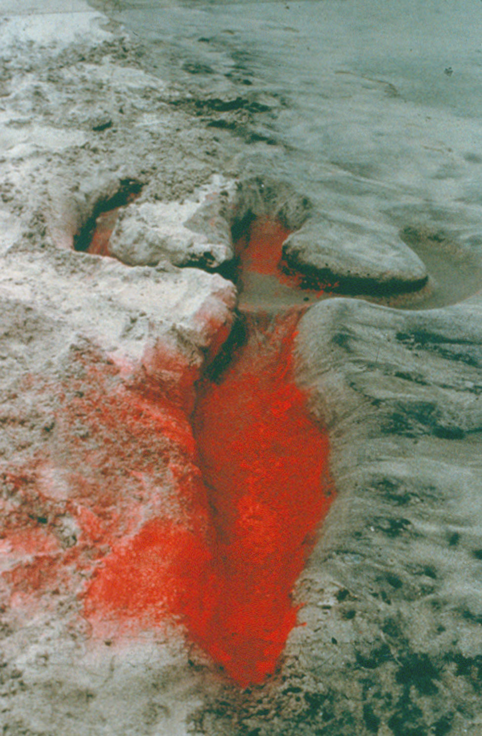 A deep impression in the earth filled with red powder in the shape of a human sillouette