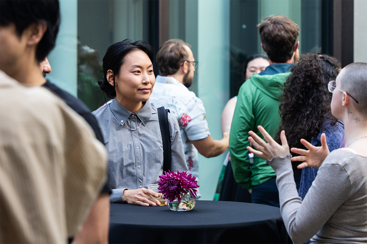 Two people standing and chatting at a tall table in a crowded courtyard