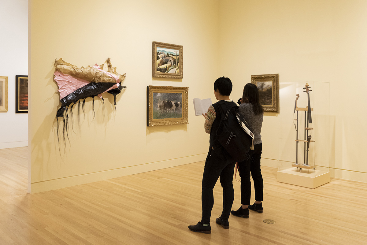 Two women standing in a gallery and looking at the art on the wall