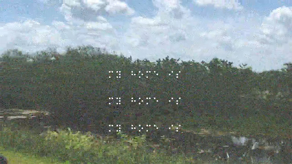 A grainy still from a video with braille writing