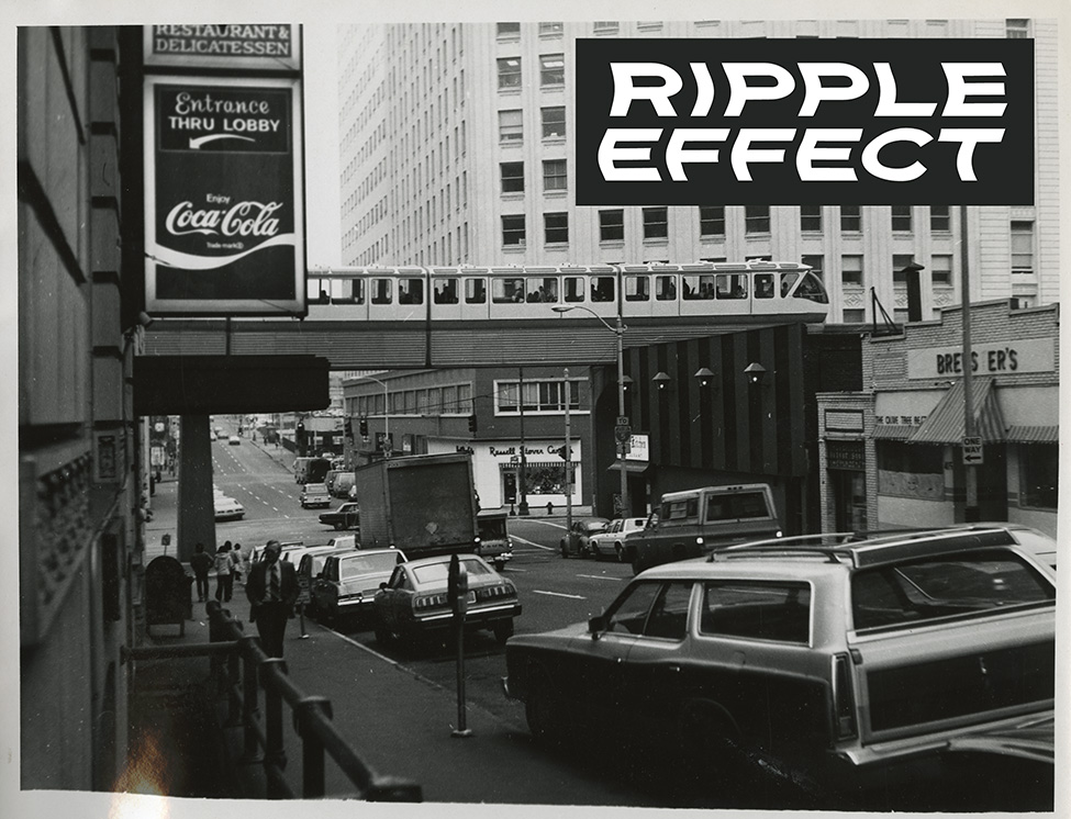 A black and white photo of a street scene in Seattle in the 80s with a monorail