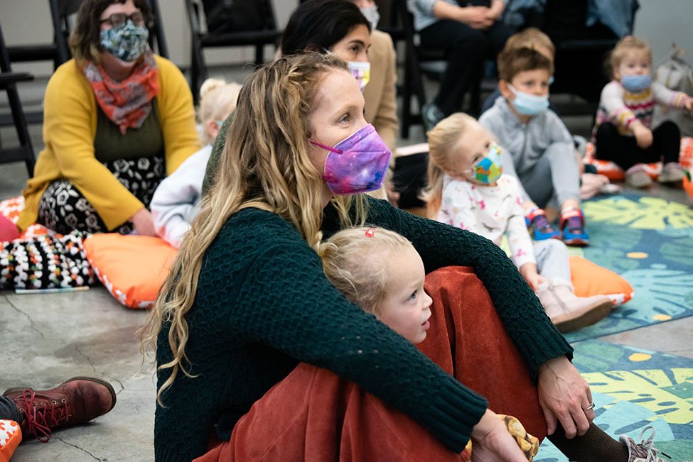 Adults and children looking up at a speaker outside the image