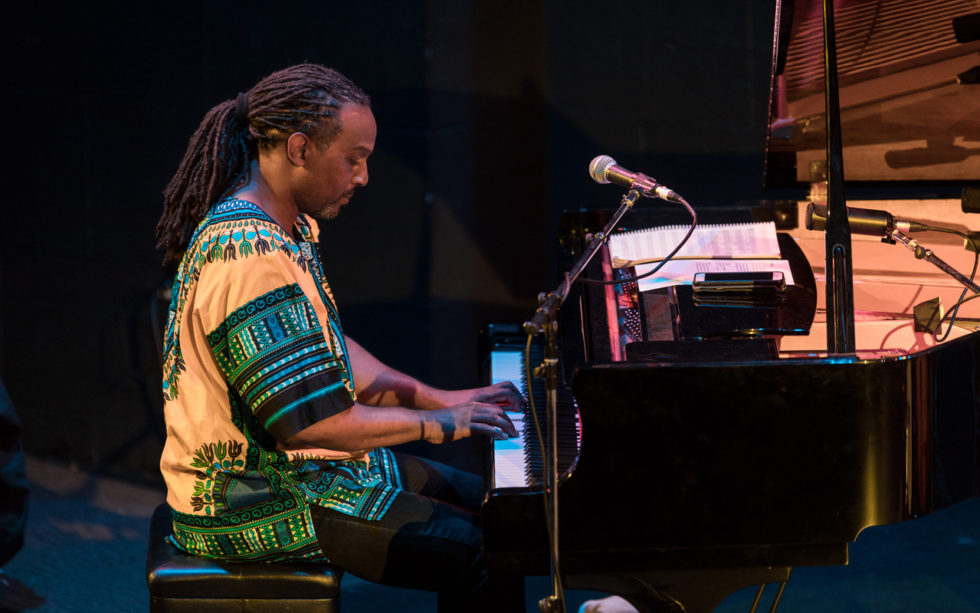 A person pictured in profile playing a grand piano