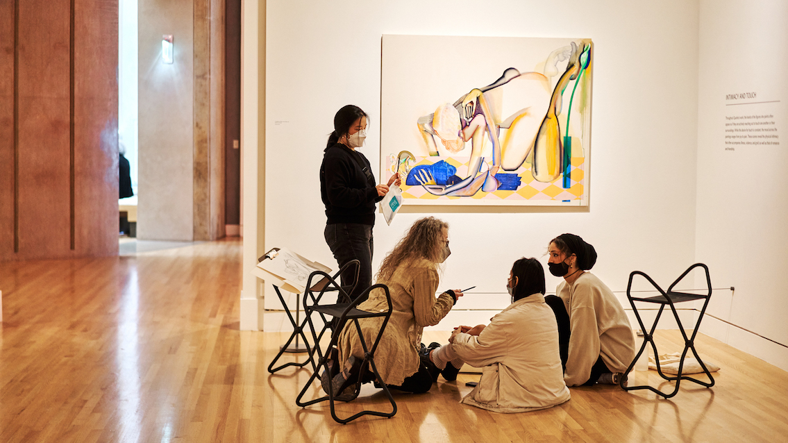 Students and teacher seated on the floor of the galleries with sketching materials