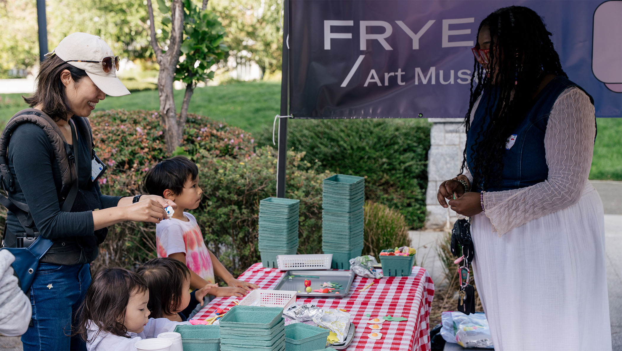 A group including children engaged in an art making activity at a farmers market booth