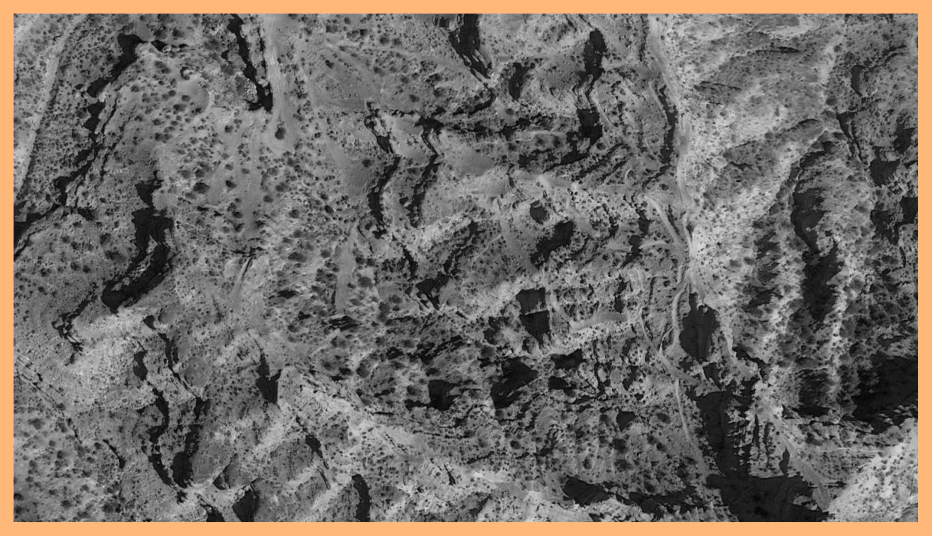 Black and white photograph of a mountain surface taken in Virgin, Utah. The image is surrounded by an orange border.