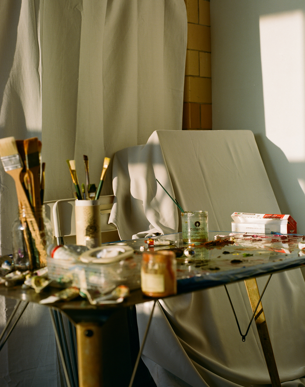 Photo of Lila Thomas's studio showing a variety of paints and other painting supplies on a table
