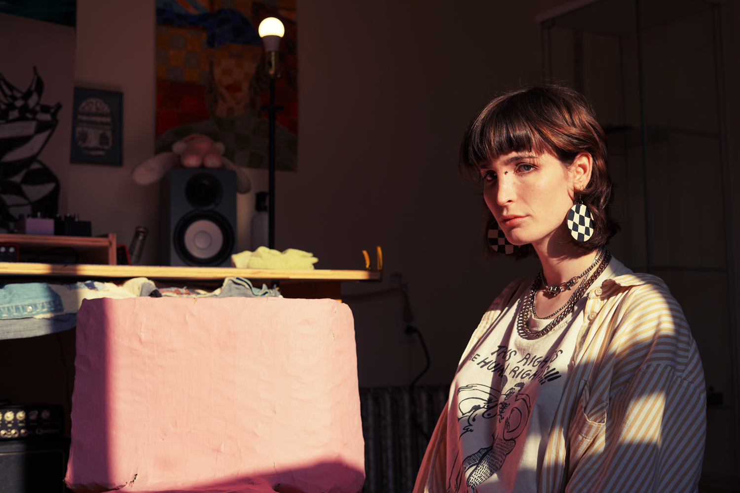 Photo of a woman with short brown hair with bangs and wearing checkerboard earrings