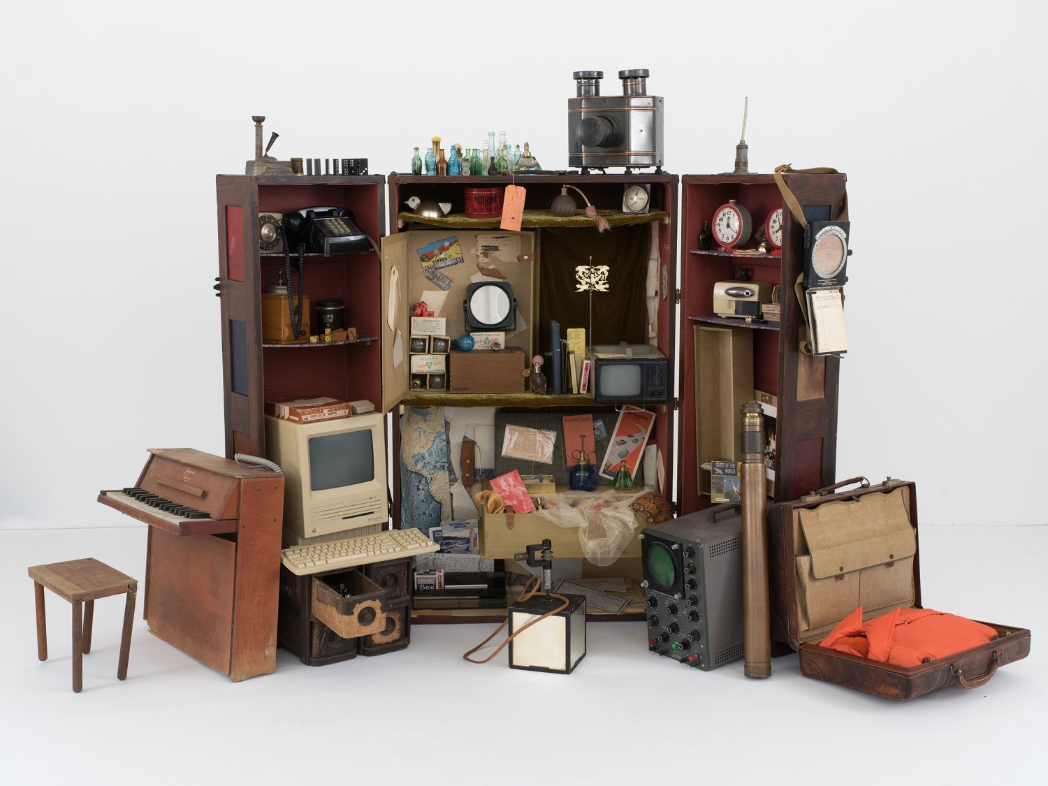 Wooden trunk that is open to display many small objects including a wooden piano, a suitcase, and an Apple II computer