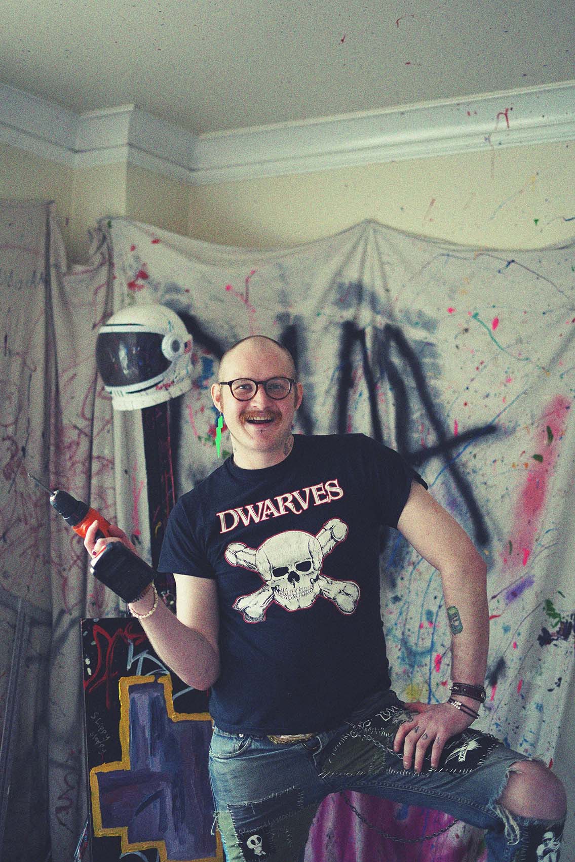 Artist with black t-shirt in their studio, holding a screwdriver