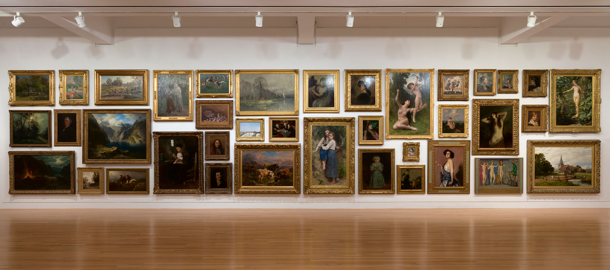 A long wall in a gallery covered in oil paintings in opulent gold frames
