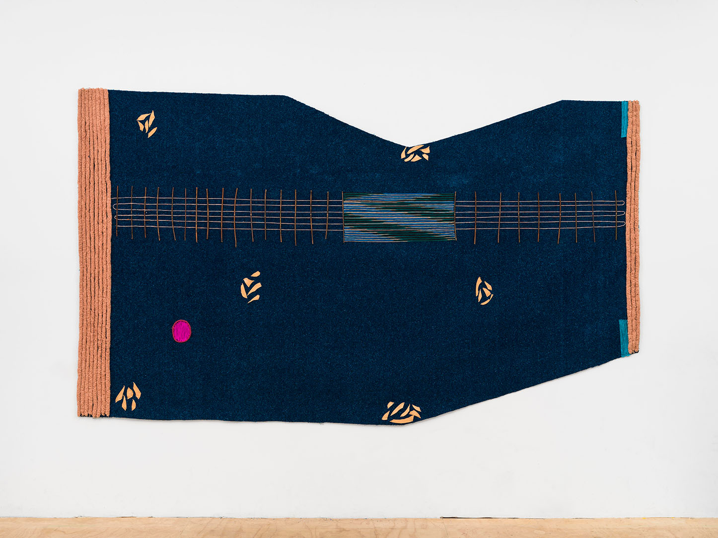 A dark blue textile artwork hanging on a white wall