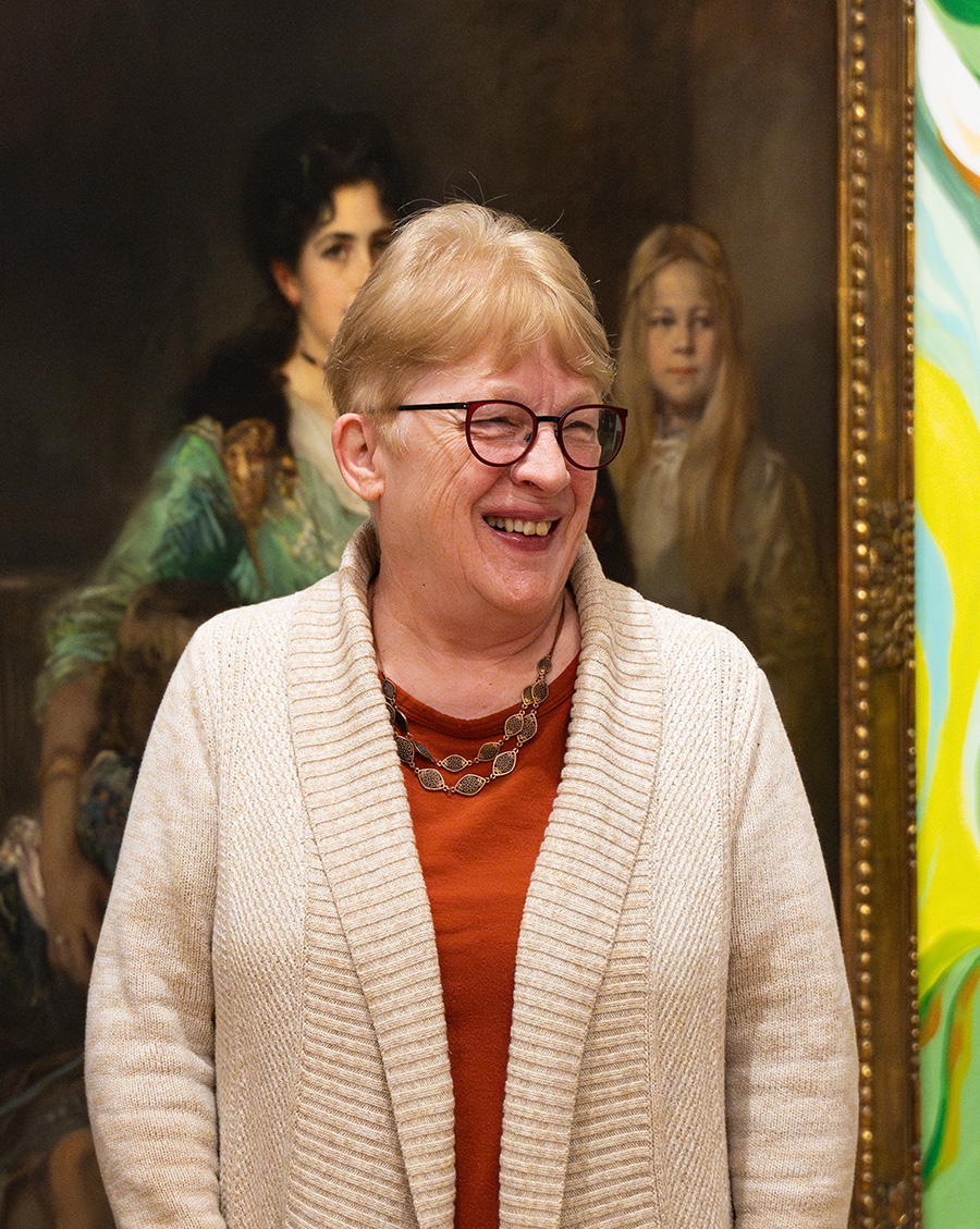 A photo of a woman in front of a painting in the Frye Salon