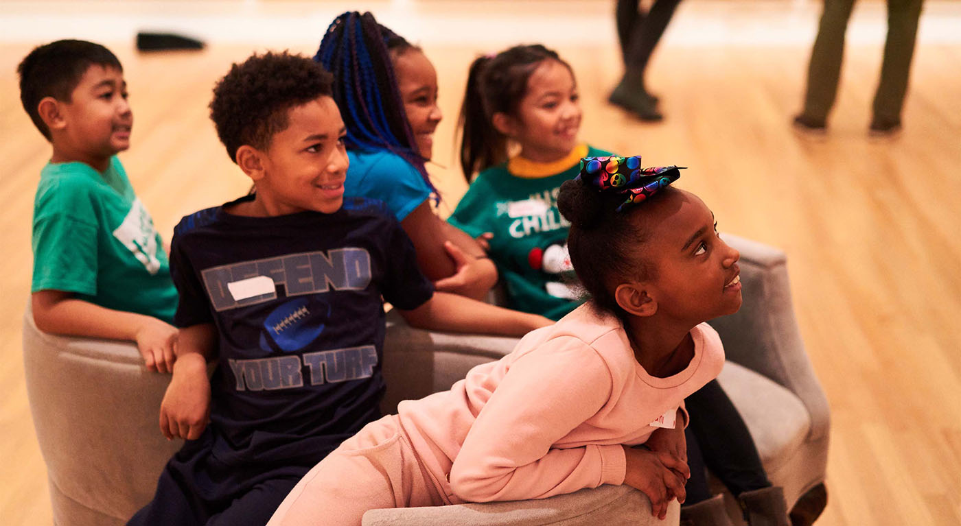 A group of children sitting on a spherical sofa chair and looking in the same direction