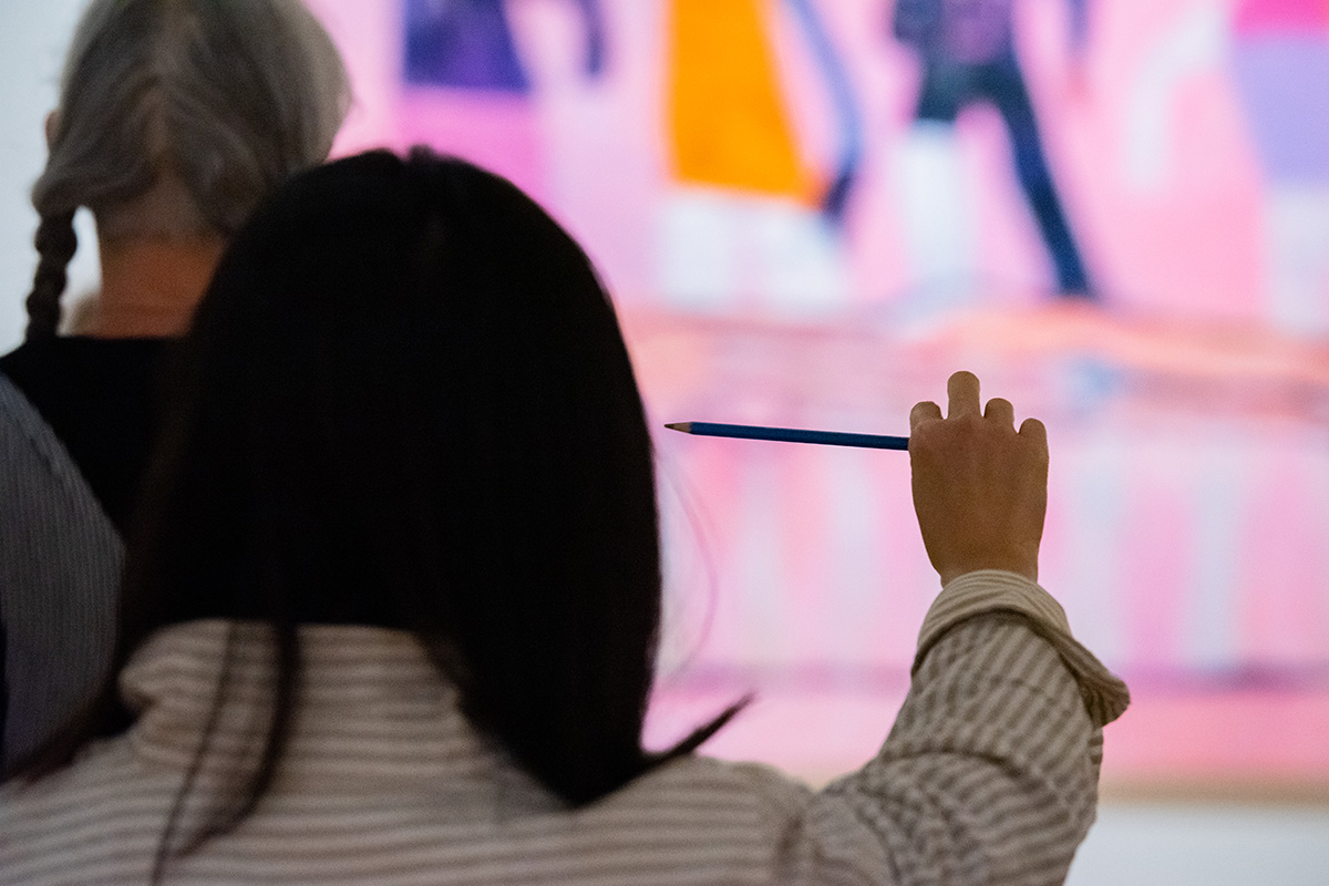 A person looking at a painting holds up a pencil at a horizontal angle