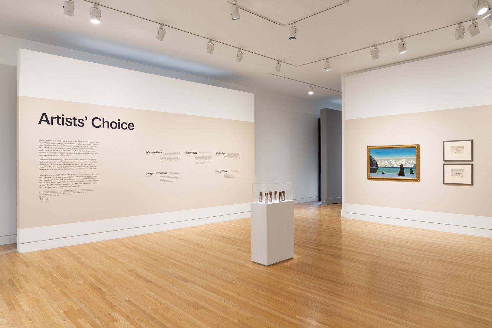 A gallery space with a large title wall of text and a group of three flat works on a perpendicular wall
