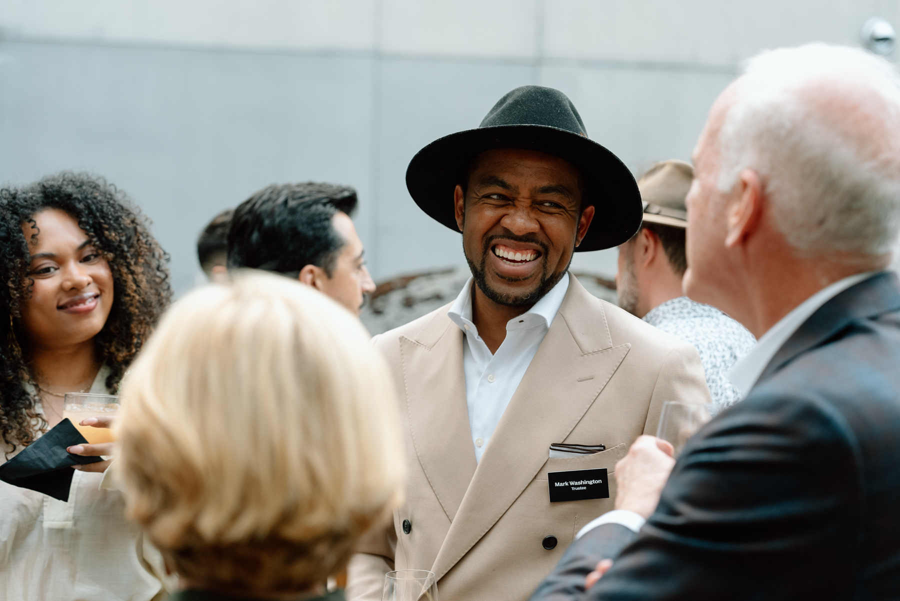 A group of people in cocktail party attire smiling and chatting in a busy outdoor courtyard