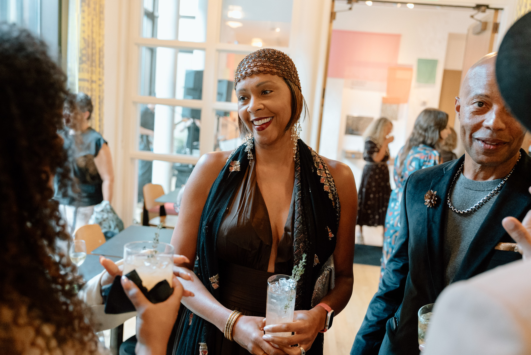 People in cocktail party attire smiling and chatting in a well lit cafe space