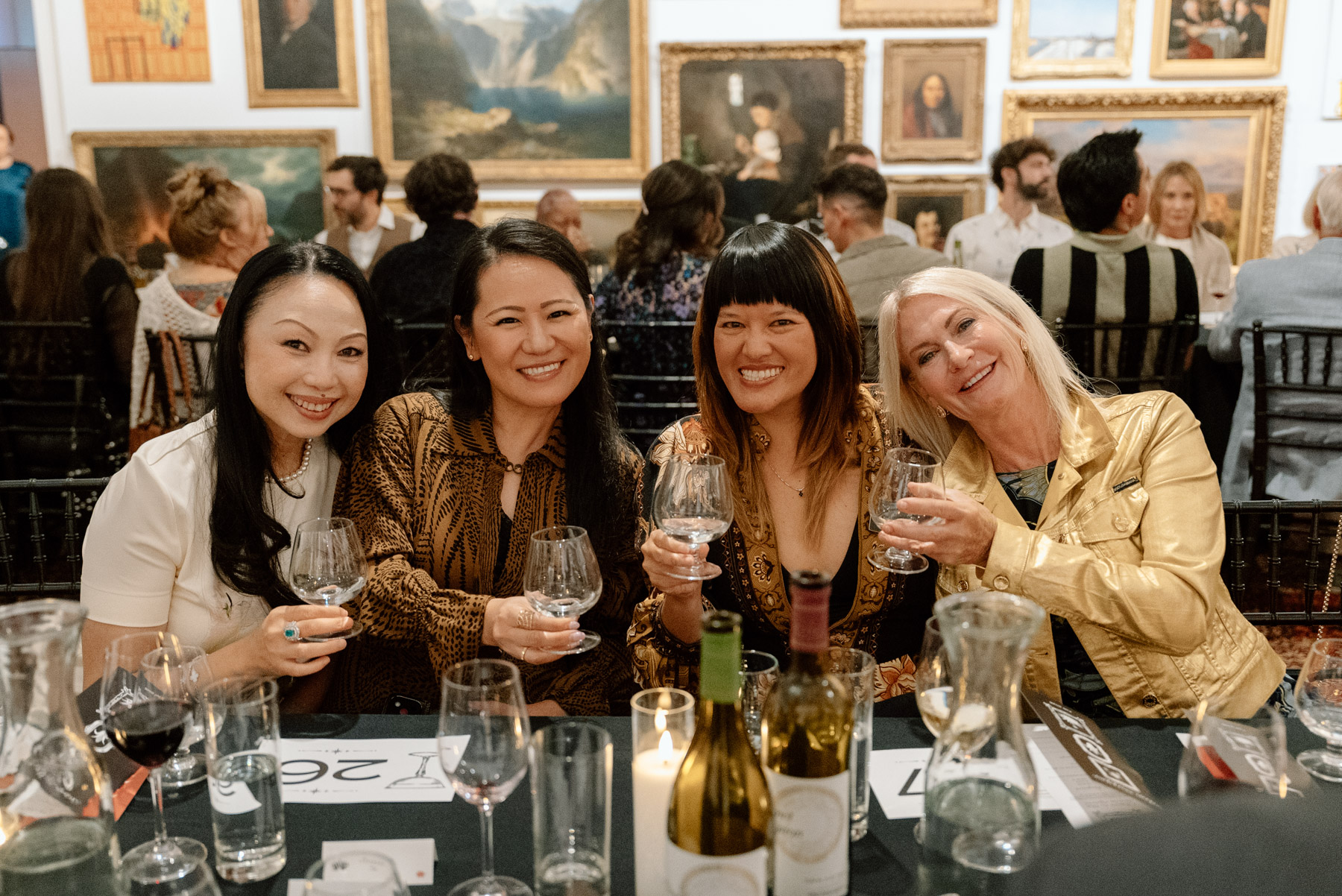 A group of seated women posing for a photo in an art gallery space