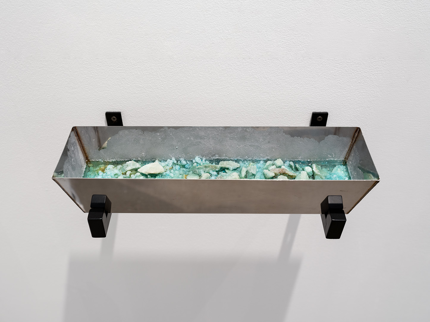 A tray mounted on a wall containing blue salt and water