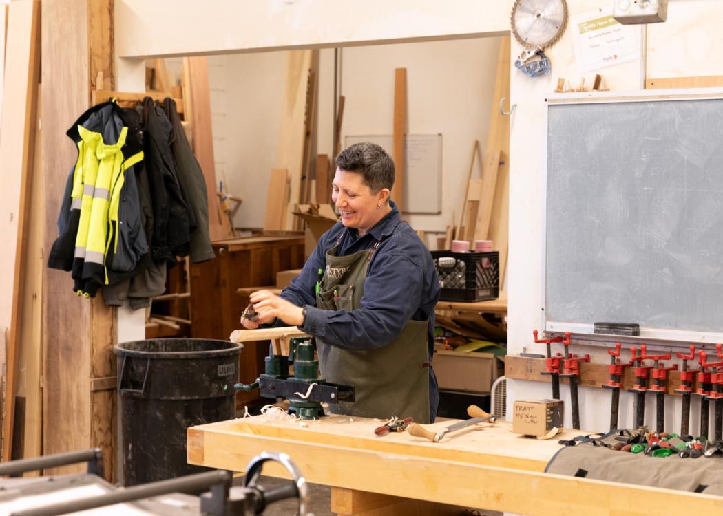 Kim McIntyre smiling and working in a woodshop