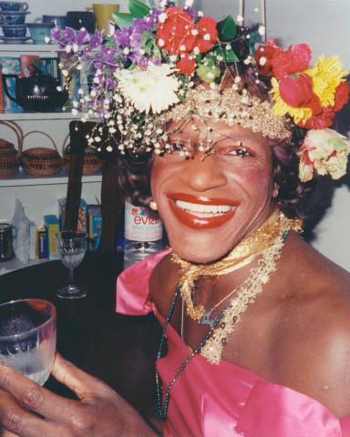 Photo of Marsha P. Johnson wearing a pink top and a flower crown