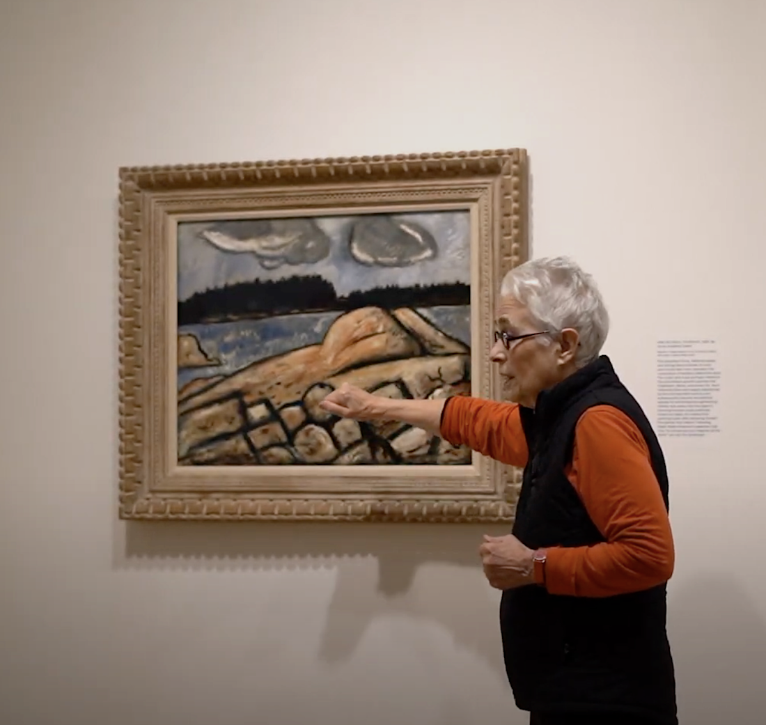 Artist Katherine Bradford gesturing to oil painting by Marsden Hartley titled After the Storm, Vinalhaven