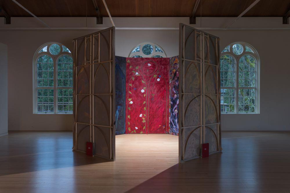 A room-sized, multi-panel art installation shaped like a hexagon, with painted interior panels.